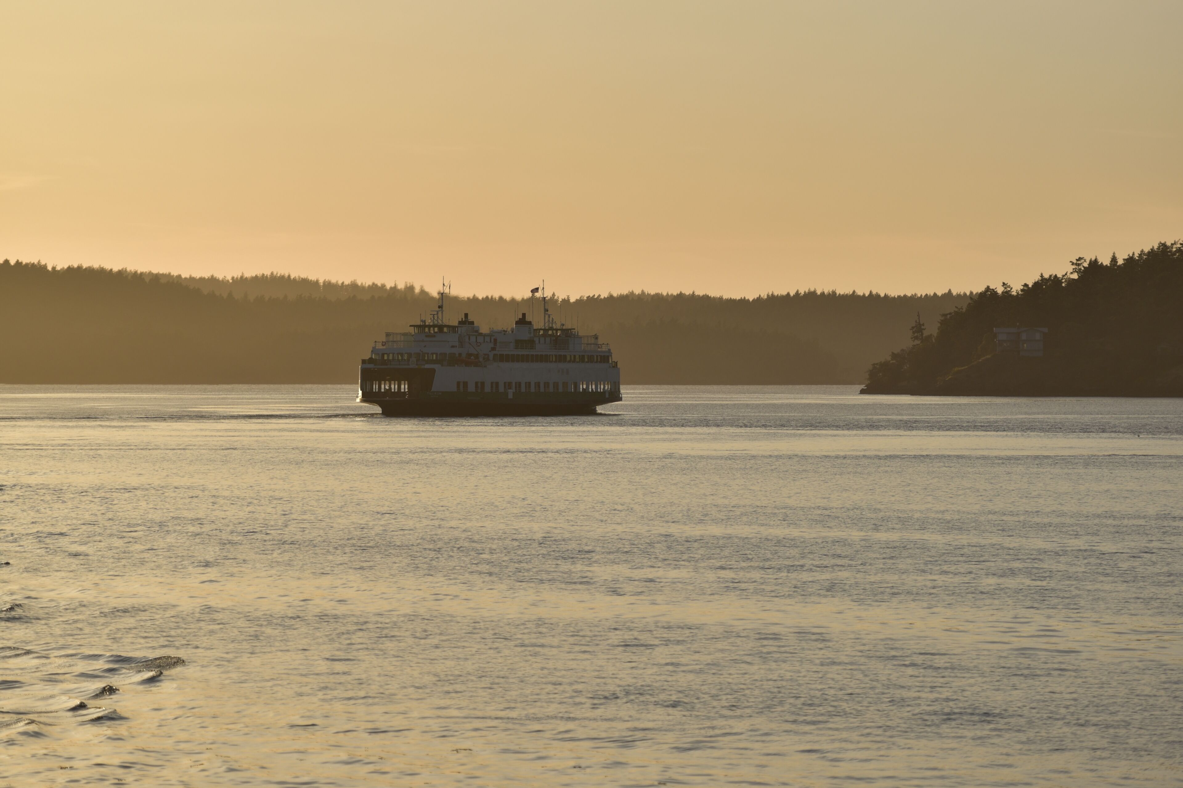 Un ferry navegando sobre aguas tranquilas durante la puesta de sol.