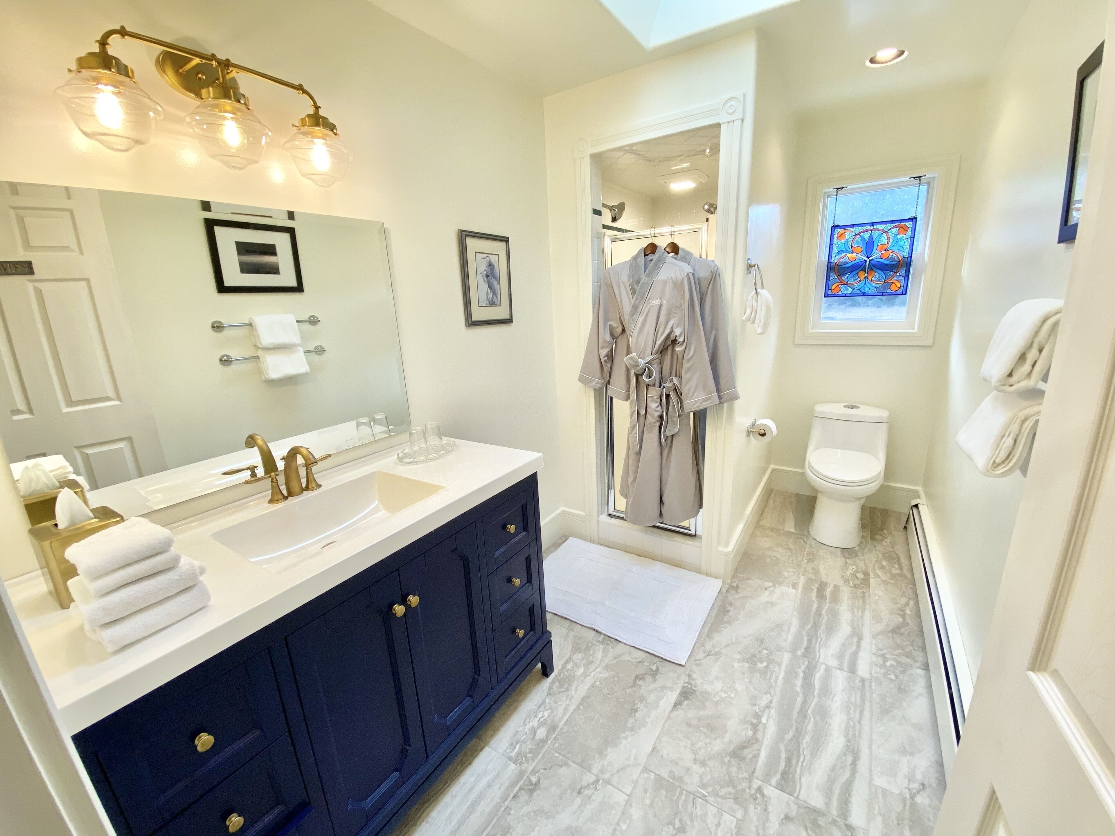 A modern bathroom with a dual sink vanity, a large mirror, and a walk-in shower.