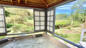 A hot tub with a wooden ceiling and a view of a garden.