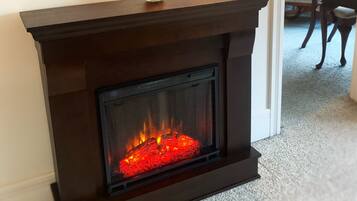 A fireplace with a glass screen, a framed picture above it, and a small bowl on the mantel.