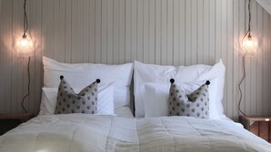 Une chambre avec un grand lit, deux tables de chevet et un plafond en pente avec des poutres apparentes.