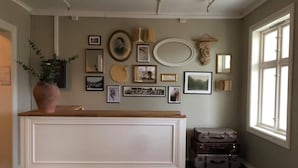 Une pièce avec un meuble blanc, des tableaux accrochés au mur et une fenêtre.