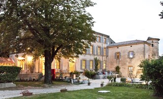 Un edificio histórico con patio, escalones de piedra y un árbol grande.