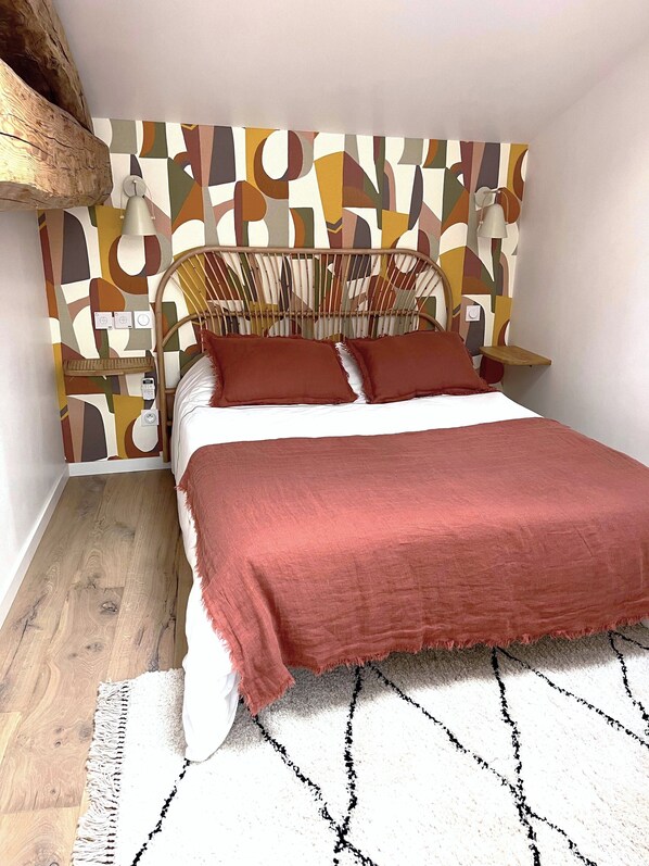 A bedroom with a bed, a headboard with a geometric pattern, a bedside table, and a nightstand. - La Grande Maison (Montmeyran)