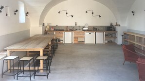A spacious kitchen with a long wooden table and chairs, a built-in oven, and a sink. - La Grande Maison (Montmeyran)