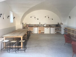 Una cocina amplia con una larga mesa de madera y sillas, horno empotrado y un lavabo.