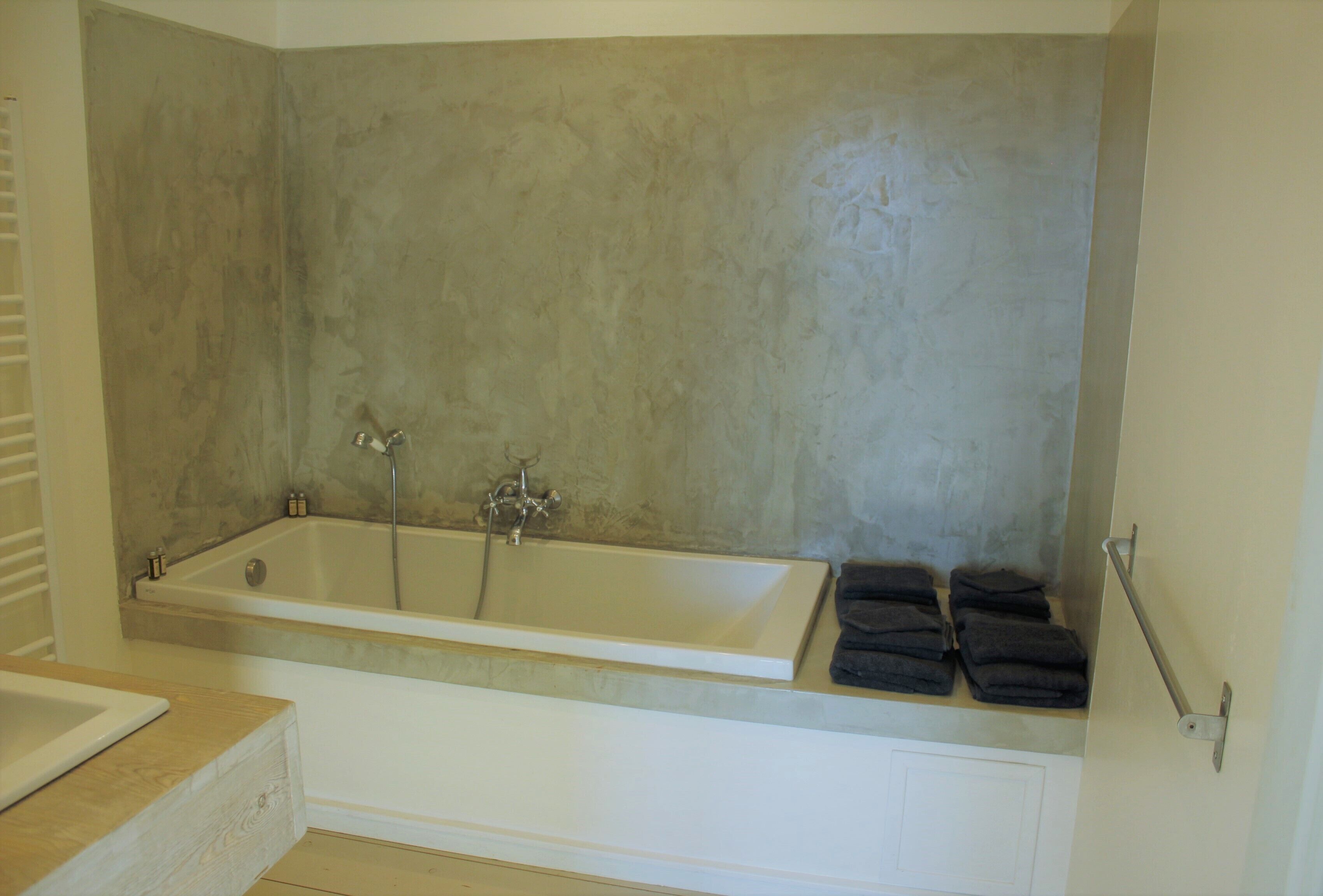 A bathroom with a bathtub, a sink, and a towel rack with folded towels.