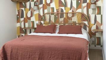 A bed with a wooden headboard, a patterned wall, and a white rug.