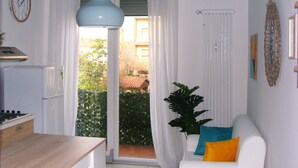 A modern living room with a white sofa, a blue pendant light, and a view of a balcony with greenery. - La Finestra sulla Fiera (Bologna)