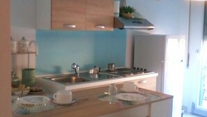 A modern kitchen with a central island, stainless steel appliances, and a clock on the wall. - La Finestra sulla Fiera (Bologna)