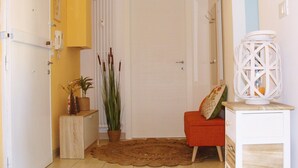 A hallway with a wooden bench, a potted plant, a white door, and a white cabinet with a lantern. - La Finestra sulla Fiera (Bologna)