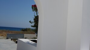 Ein modernes Bauwerk mit weißer Fassade, freiem Blick auf den Strand und einer roten Blume in einem Bogen.