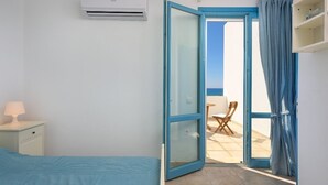 Ein Schlafzimmer mit einem Bett, einem Nachttisch, einer Klimaanlage und einer Glastür, die zu einem Sitzbereich im Freien führt.