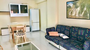 A living room with a sofa, a glass coffee table, a dining table with chairs, a refrigerator, and a TV mounted on the wall. - GREAT APARTMENT FOR HOLIDAY RENT RINCON DE LOIX R059 (Benidorm)