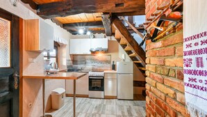 Una cucina compatta con piano cottura, lavello ed elettrodomestici moderni, caratterizzata da pareti in mattoni a vista e travi in legno.