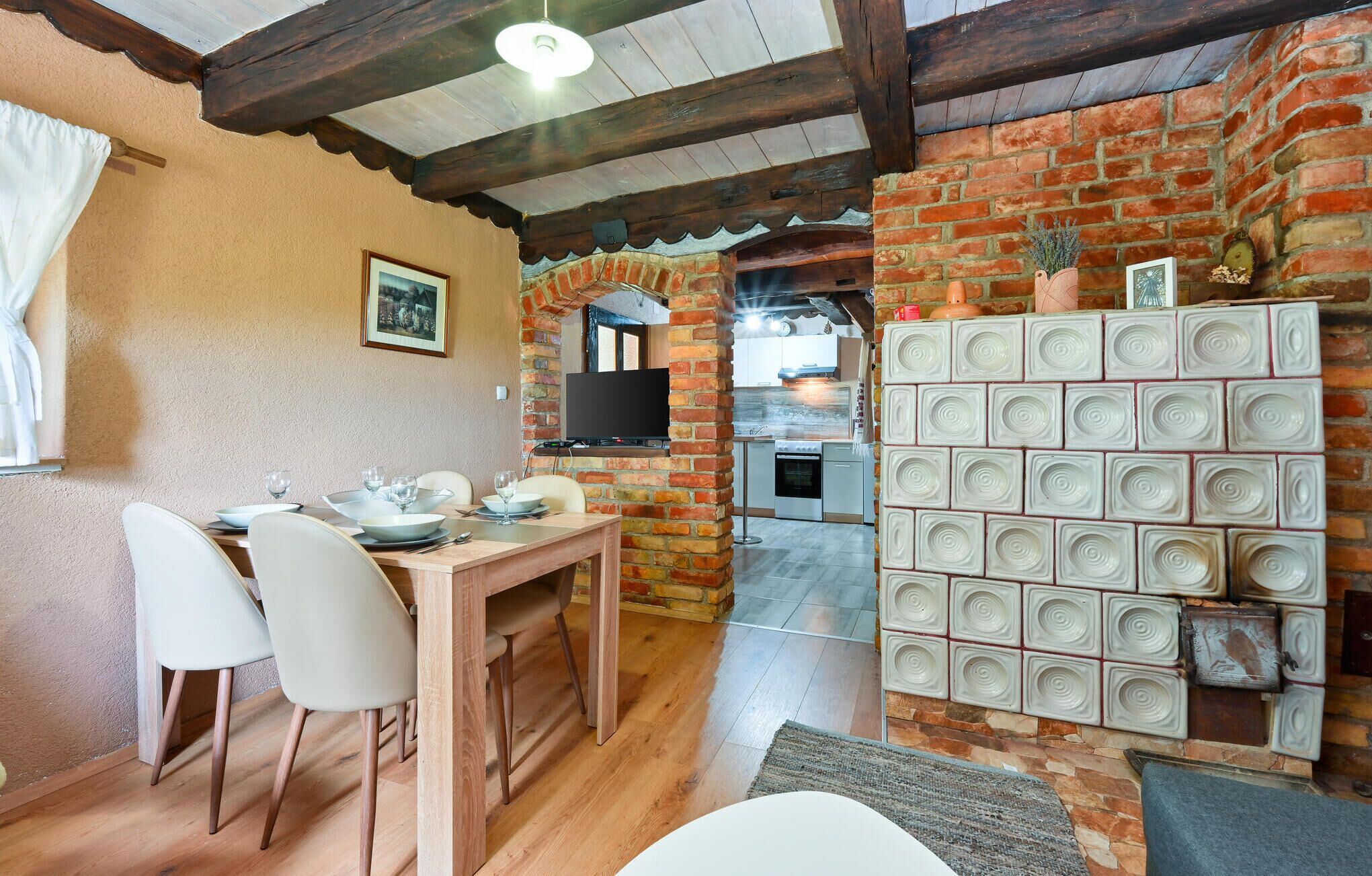 A cozy dining area with a brick wall, a wooden table, and white chairs.