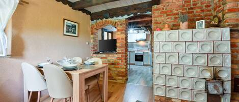A cozy dining area with a brick wall, a wooden table, and white chairs.