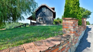 Una rustica casa di legno con tetto spiovente, un portico e un muro in mattoni.