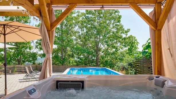 Una vasca idromassaggio con vista su una piscina e alberi.