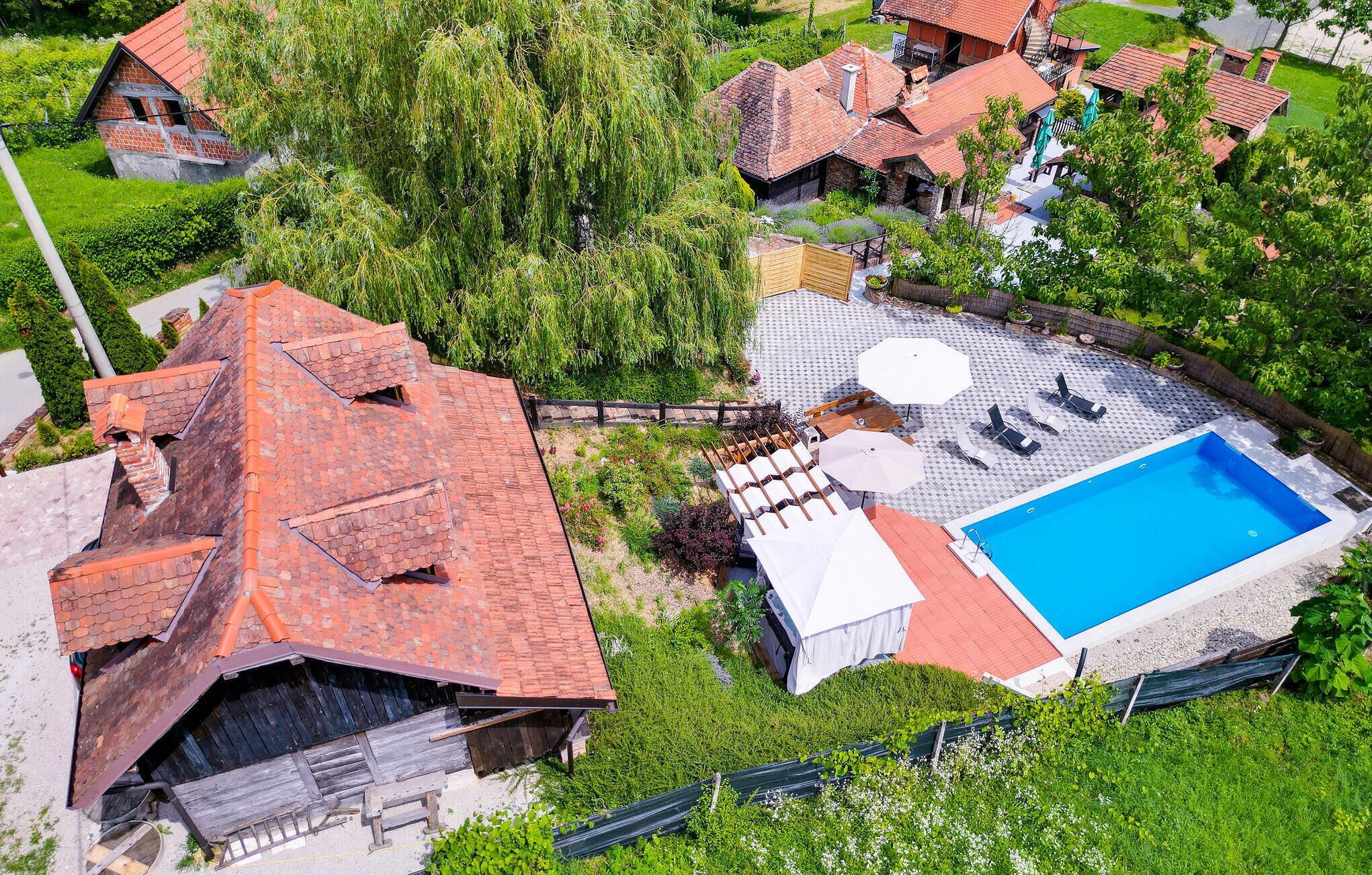 Eine Vogelperspektive eines Wohnhauses mit Schwimmbad, Terrassenbereich mit Sitzgelegenheiten und Garten.