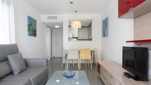 Un soggiorno moderno con un divano, un tavolino in vetro, una TV e un'area pranzo con sedie e tavolo.