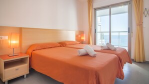 Une chambre d’hôtel avec deux lits, une table de chevet et une fenêtre avec des rideaux.