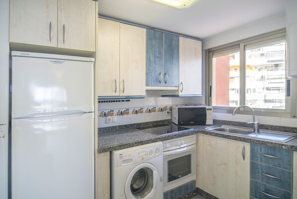 A compact kitchen with a washing machine, microwave, and a sink. - First line / Wifi / Spa / Seaviews / Heated pool / Pets (Calpe)