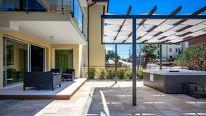 Un patio exterior moderno con pérgola, mobiliario para exteriores y un jacuzzi.