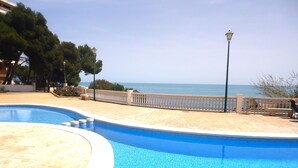 A swimming pool with a view of the sea, surrounded by a white fence and trees. - Edison Bungalow LEK (Peñiscola)