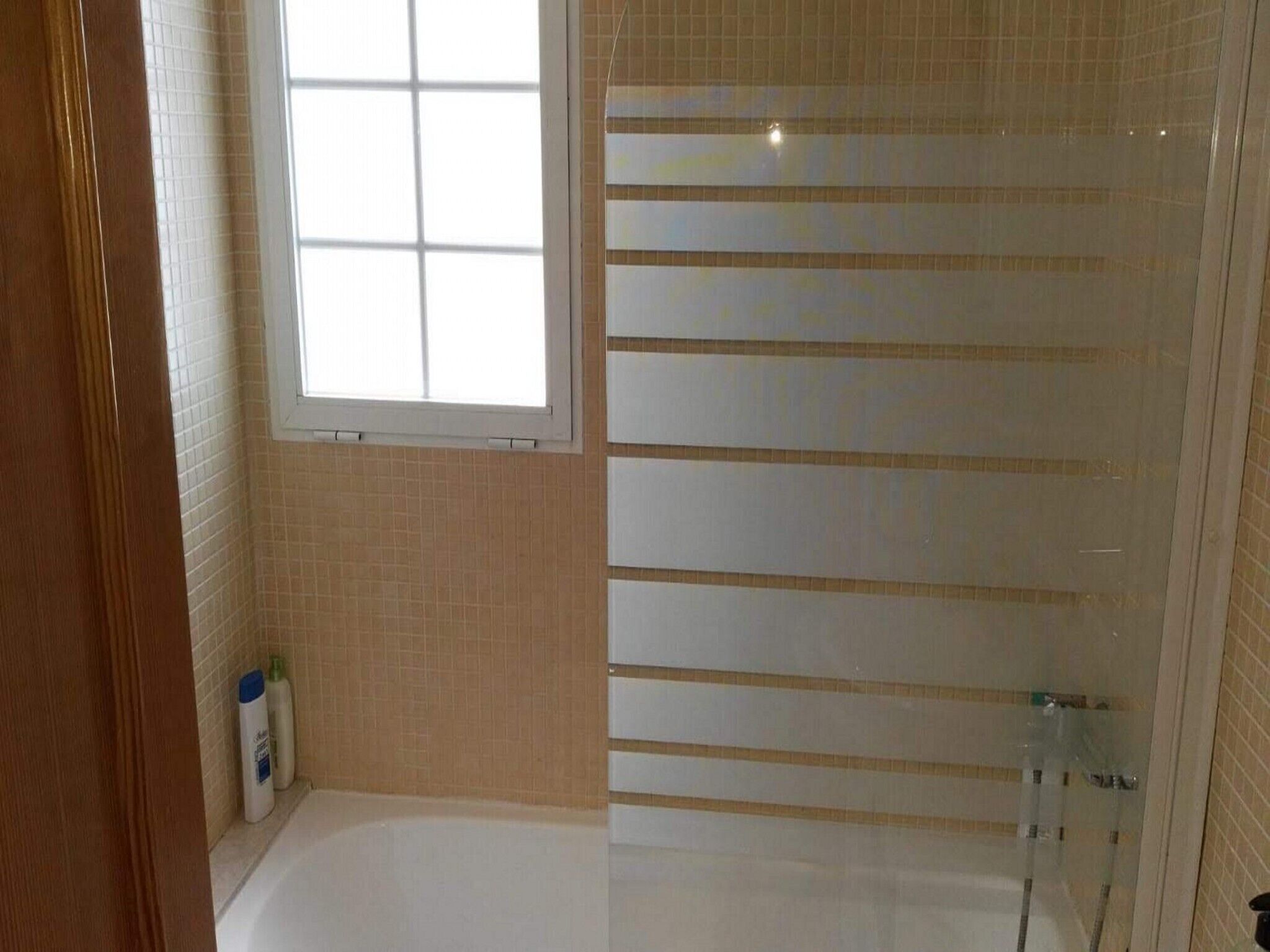 Un baño con bañera, ventana y zona de ducha.