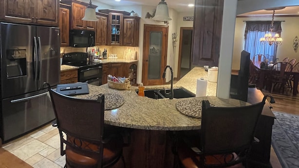 A modern kitchen with granite countertops, stainless steel appliances, and dark wooden cabinets. - Golf Getaway-Large Families Welcome! Only 10 minutes from the Airport!  (Springfield)