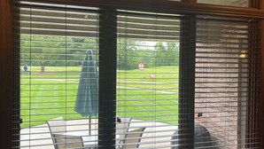 A room with a large window with blinds, a patio area with outdoor furniture, and a view of a grassy yard. - Golf Getaway-Large Families Welcome! Only 10 minutes from the Airport!  (Springfield)