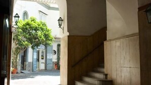 Un corridoio ad arco con una scala che conduce a un livello superiore. Si nota una pianta in vaso sullo sfondo.