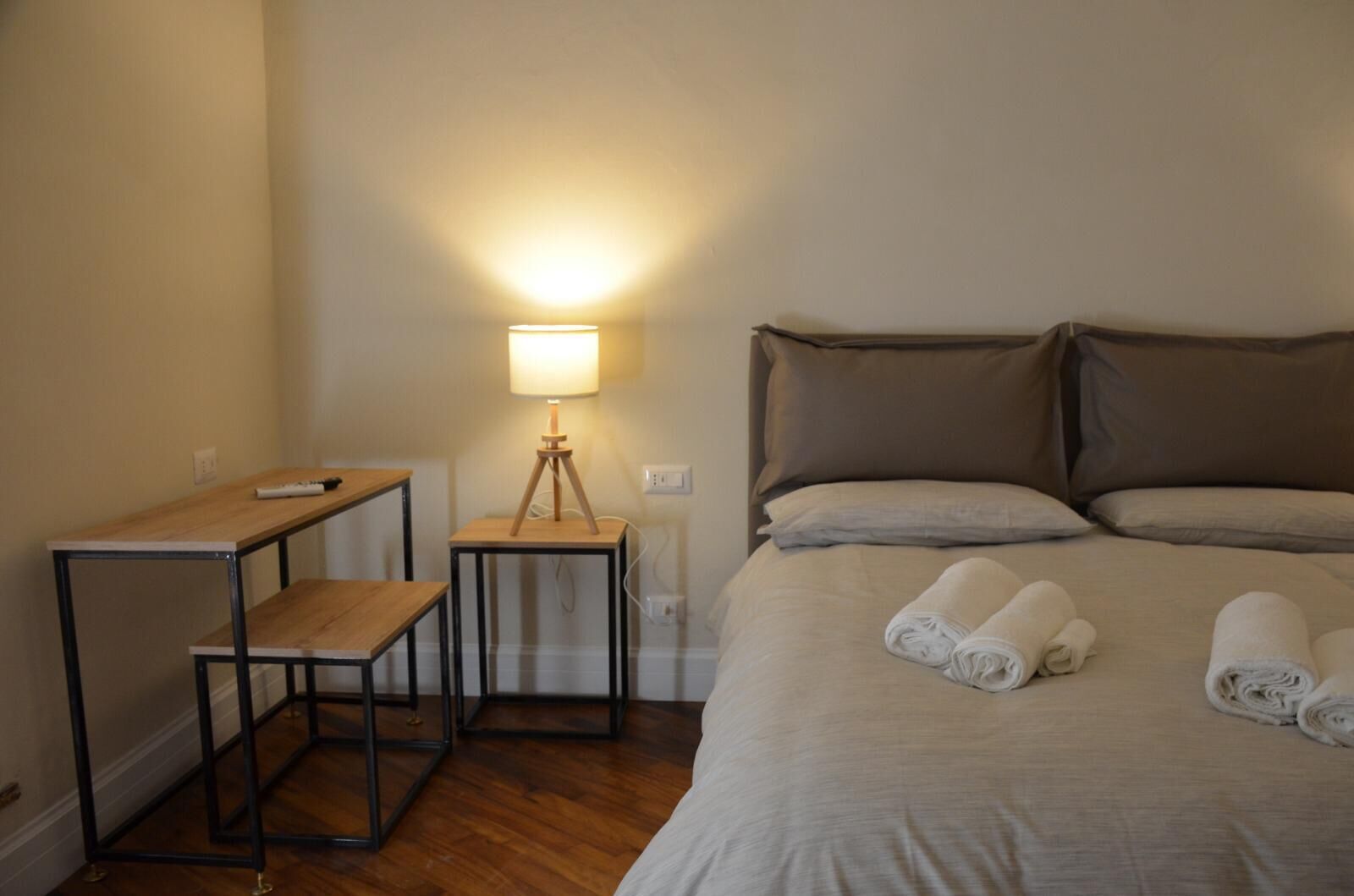 A hotel room with a bed, a desk, and a lamp.