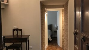 Un corridoio con pavimento in legno, un tavolo da pranzo con sedie, una libreria e una porta che dà su un'altra stanza.