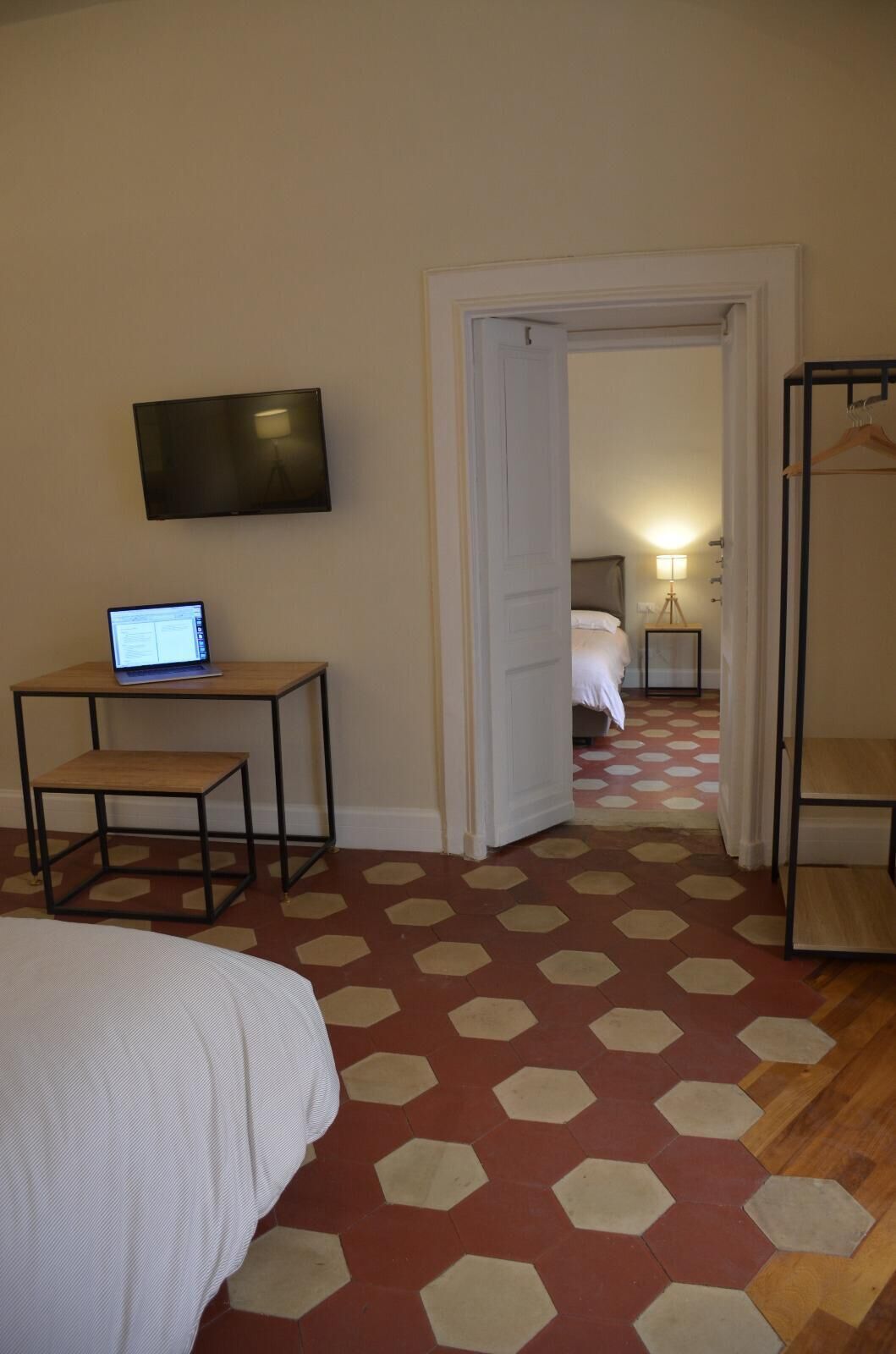 Une chambre d’hôtel comprenant un lit, un bureau avec un ordinateur portable, un téléviseur fixé au mur et une armoire.