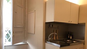 Cucina compatta con lavello, pensili e finestra vista sul verde.
