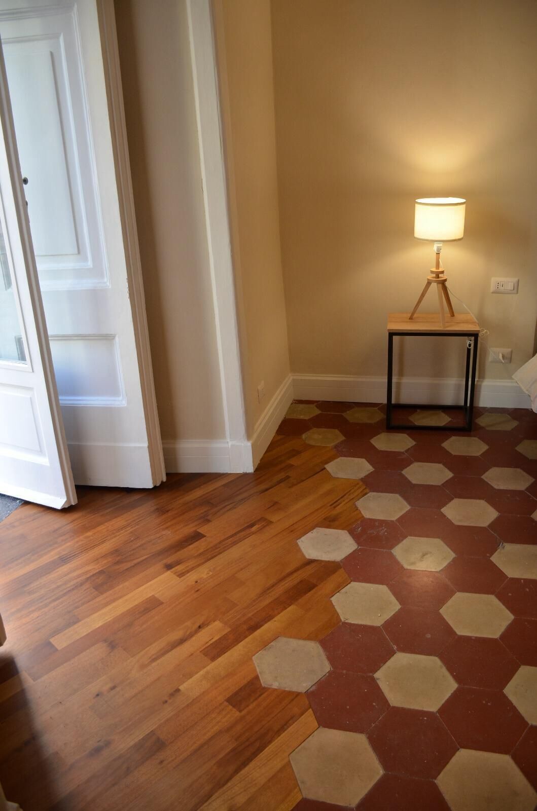A hallway with wooden flooring and a hexagonal patterned rug.