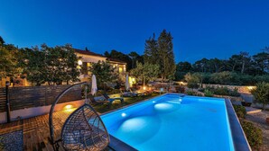 A swimming pool with a wooden deck, lounge chairs, and a house in the background. - Awesome home in Sibenik (Sibenik)
