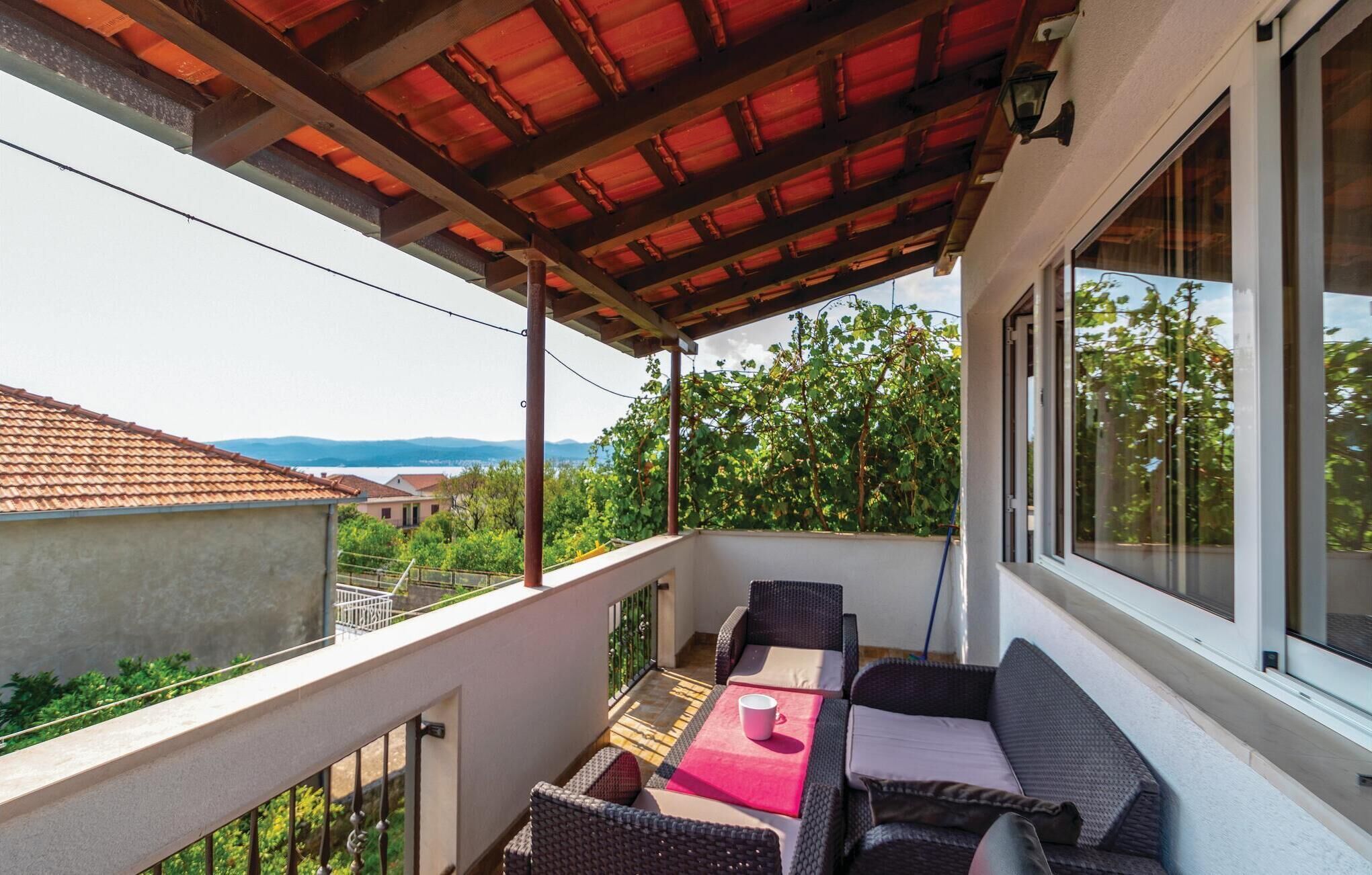 A balcony with outdoor furniture, a pergola, and a view of the surrounding area.