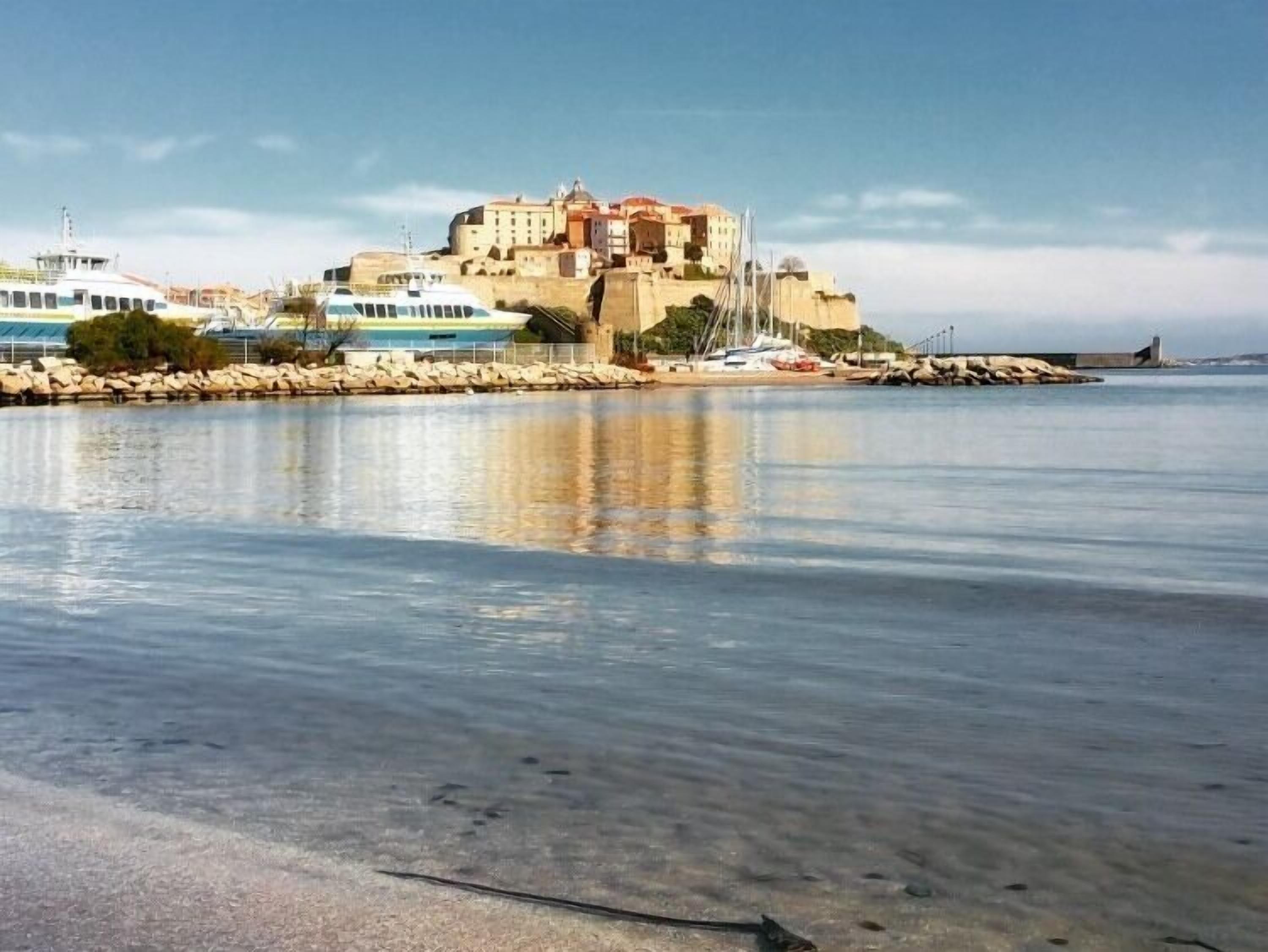A coastal building with a waterfront view, a clear sky, and calm water.