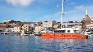 A waterfront with a large orange boat docked near buildings. - Studio Orsoni - See View (Calvi)