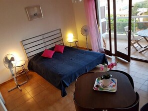 Une chambre à coucher avec un lit, des tables de chevet, un ventilateur et une table avec un plateau.