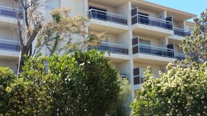 A multi-story building with balconies, surrounded by greenery. - Studio Orsoni - See View (Calvi)