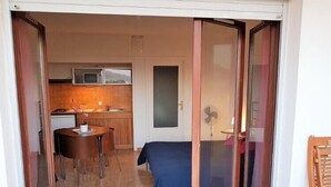 A compact living space with a kitchenette, a dining area, and a bed. - Studio Orsoni - See View (Calvi)
