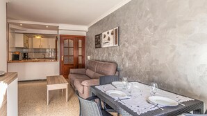Een compacte woonruimte met een kitchenette, een eethoek met een tafel voor twee personen en een bank.