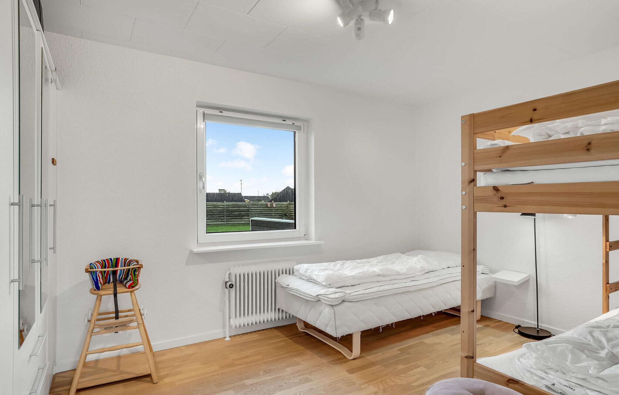 Een slaapkamer met een stapelbed, een raam met uitzicht, een radiator en een houten ladder.