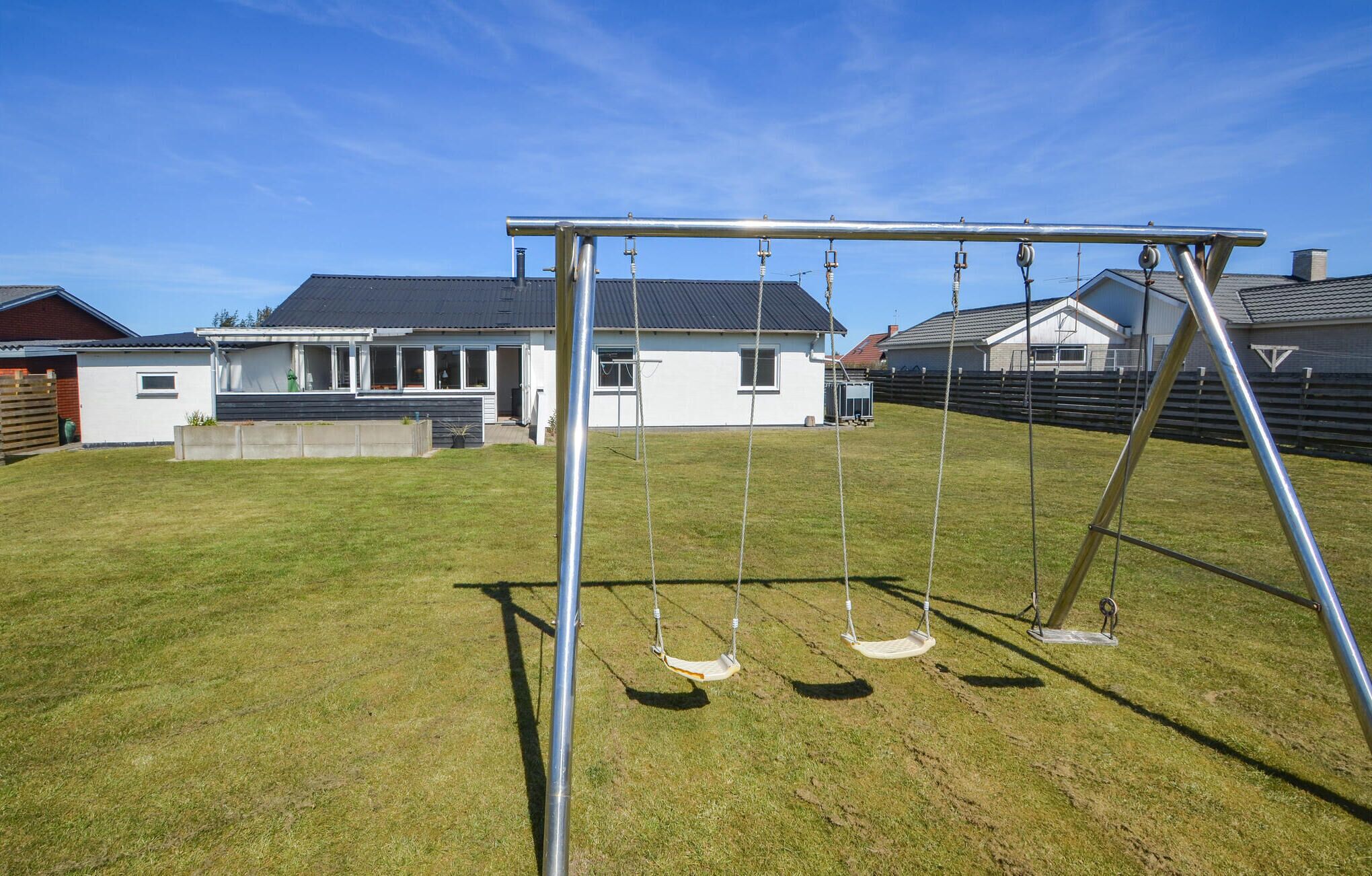 A swing set in a backyard with a house in the background.