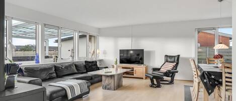Ett modernt vardagsrum med en soffa, en tv, ett matbord och en stol.