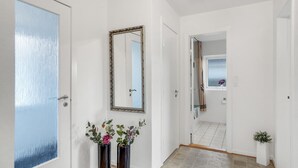 A hallway with a white door, a mirror, and two potted plants. - 2 bedroom lovely home in Thisted (Thisted)